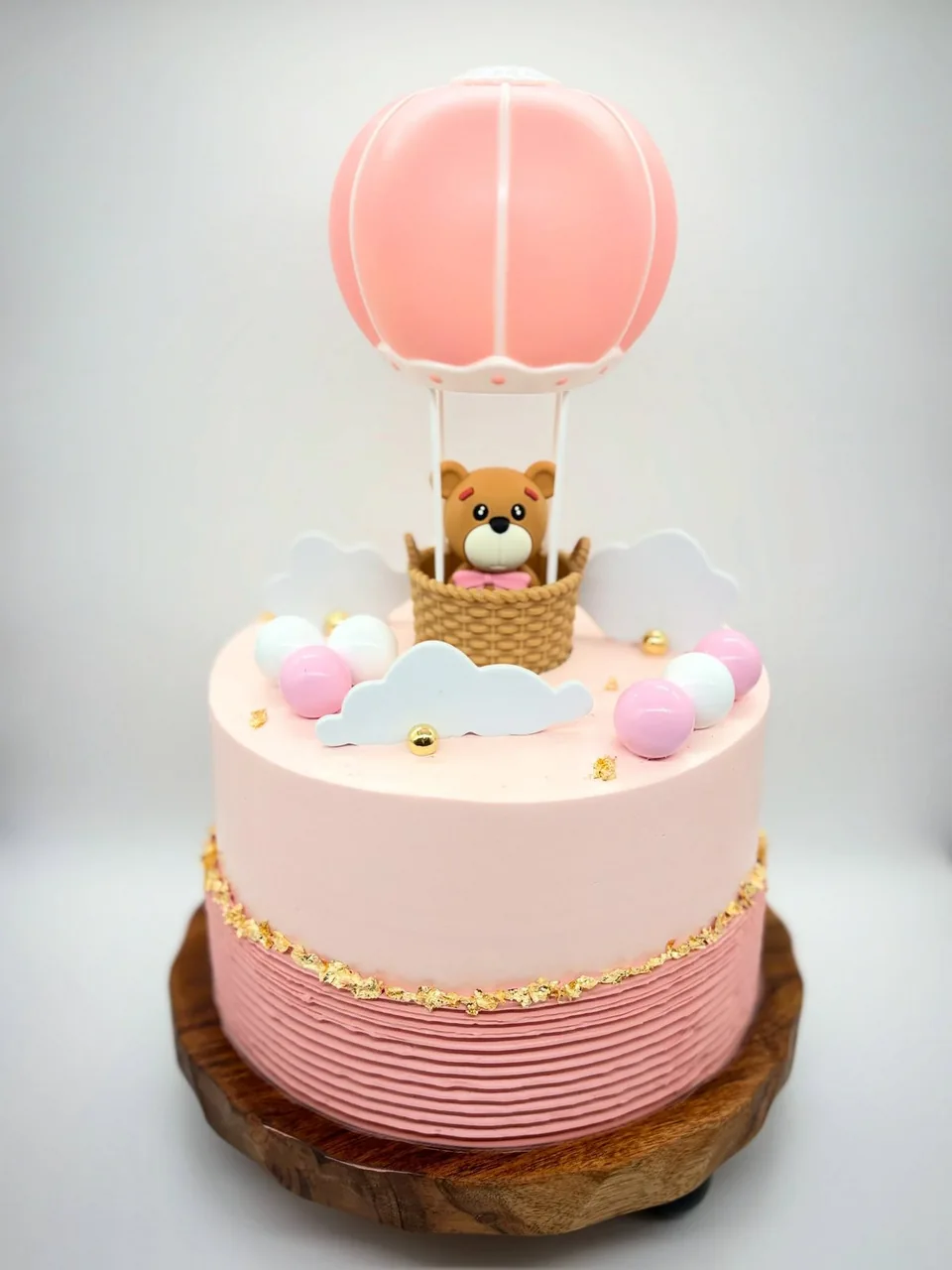 Pastel personalizado rosado con globo aerostático, osito y nubes